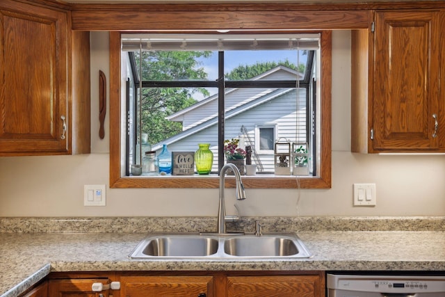 kitchen with a sink, brown cabinets, white dishwasher, and light countertops