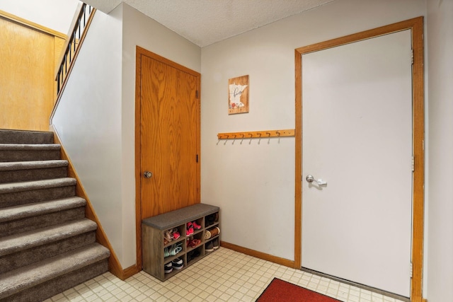 interior space featuring stairs, baseboards, and a textured ceiling