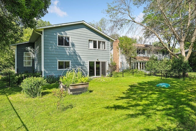 back of property with a garden, a yard, and a fenced backyard