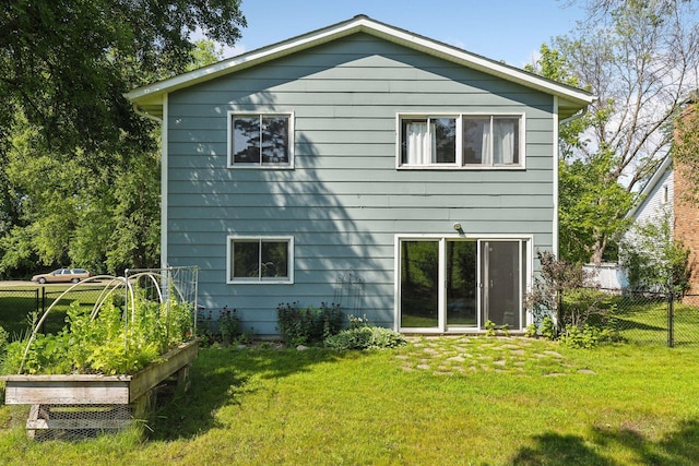 back of house featuring a yard, a vegetable garden, and fence