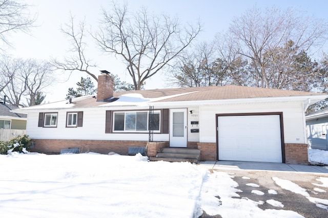 single story home featuring brick siding, an attached garage, a chimney, and driveway