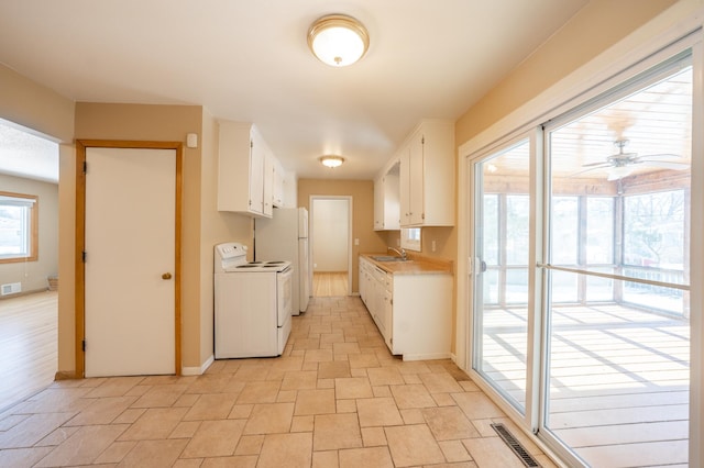 kitchen with visible vents, a sink, white cabinetry, white appliances, and light countertops