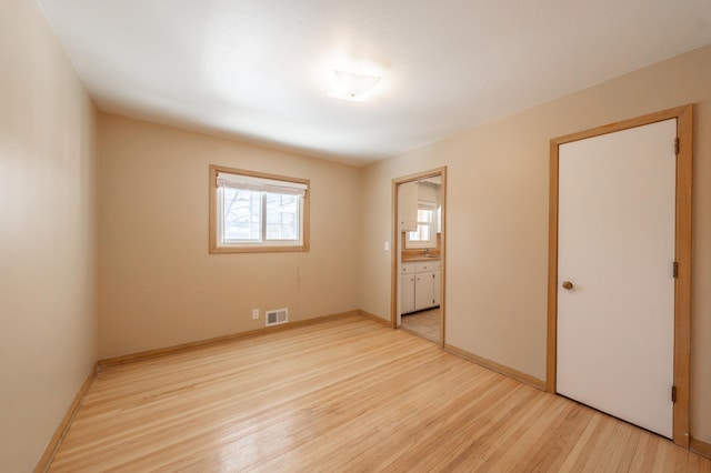 unfurnished bedroom featuring a sink, baseboards, visible vents, and light wood-type flooring