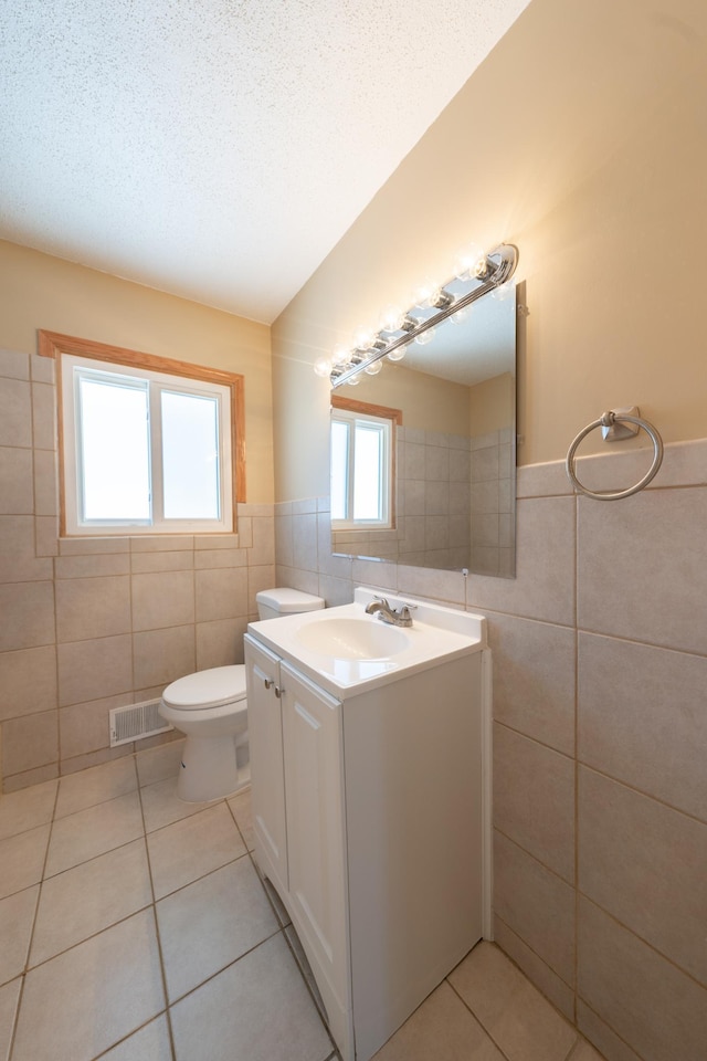 bathroom with visible vents, a textured ceiling, tile walls, and tile patterned flooring