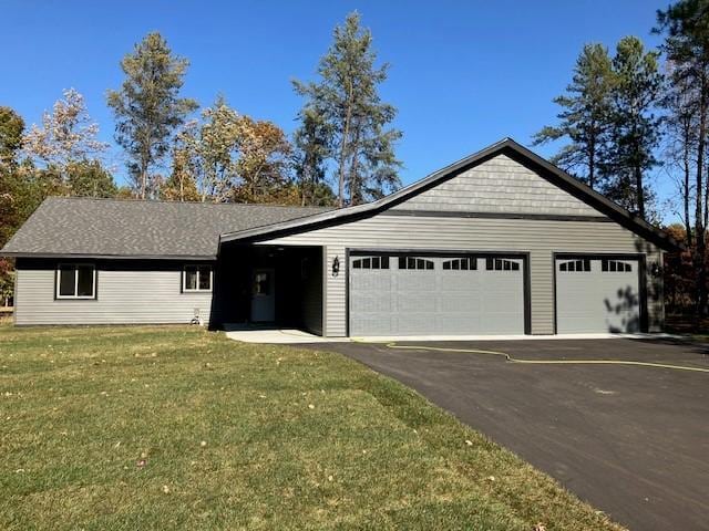 ranch-style home featuring driveway, a front lawn, and an attached garage