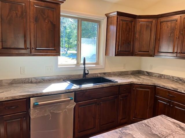 kitchen featuring dishwasher, dark brown cabinetry, and a sink