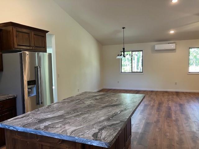 kitchen featuring lofted ceiling, an AC wall unit, dark wood-type flooring, high quality fridge, and a center island