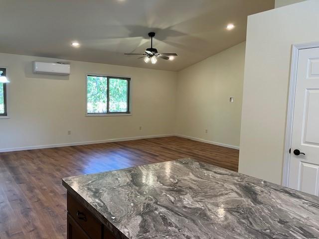 unfurnished room featuring a ceiling fan, wood finished floors, baseboards, recessed lighting, and an AC wall unit