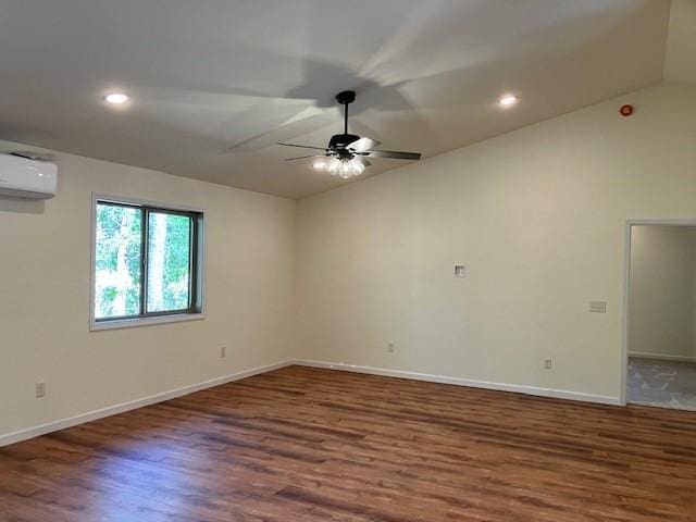 empty room with baseboards, an AC wall unit, lofted ceiling, and wood finished floors