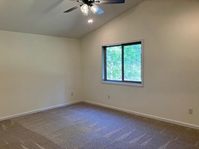 spare room with vaulted ceiling, baseboards, and dark colored carpet