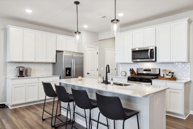 kitchen with dark wood-style flooring, appliances with stainless steel finishes, white cabinetry, and a sink