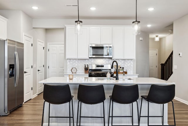 kitchen with dark wood-style flooring, white cabinets, visible vents, and appliances with stainless steel finishes