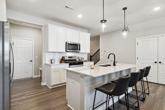 kitchen with visible vents, dark wood-type flooring, a sink, tasteful backsplash, and appliances with stainless steel finishes