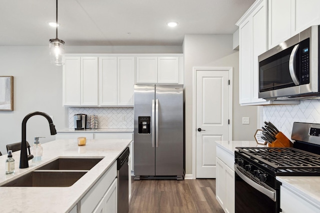 kitchen with dark wood-style floors, a sink, appliances with stainless steel finishes, white cabinetry, and decorative light fixtures