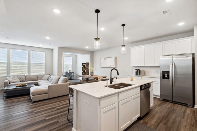 kitchen featuring a sink, open floor plan, dark wood-style floors, stainless steel appliances, and decorative backsplash