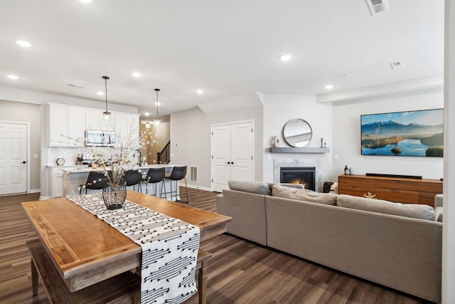 living area featuring visible vents, recessed lighting, dark wood-type flooring, and a lit fireplace