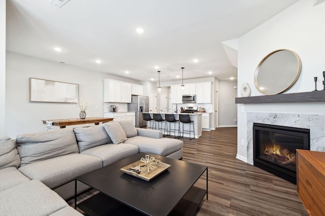 living area with recessed lighting, baseboards, dark wood-style floors, and a high end fireplace