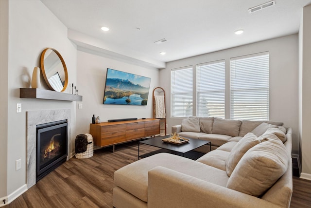 living area featuring visible vents, baseboards, dark wood finished floors, and a fireplace