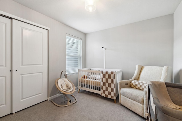 carpeted bedroom featuring a closet, baseboards, and a nursery area