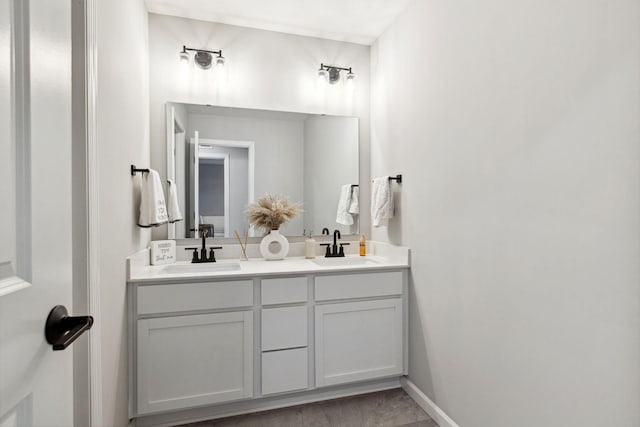 bathroom featuring a sink, baseboards, and double vanity