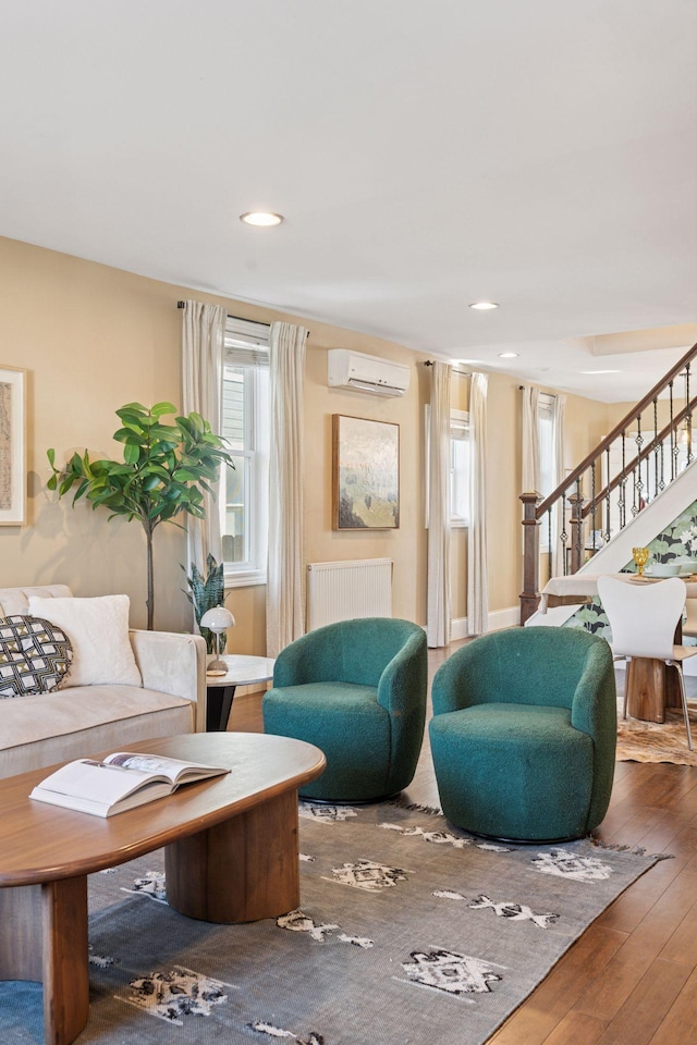 living area featuring an AC wall unit, hardwood / wood-style floors, recessed lighting, stairway, and radiator