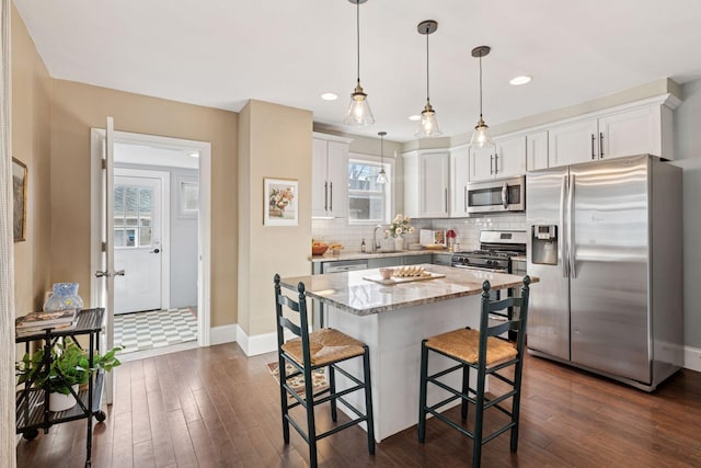 kitchen featuring dark wood finished floors, a sink, tasteful backsplash, and stainless steel appliances