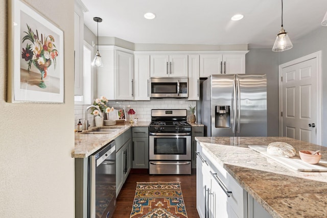 kitchen featuring a sink, stainless steel appliances, decorative backsplash, light stone countertops, and dark wood-style flooring