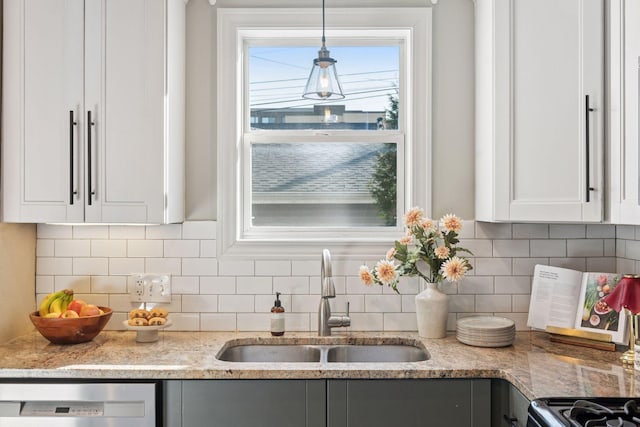 kitchen featuring decorative light fixtures, dishwasher, light stone counters, white cabinets, and a sink