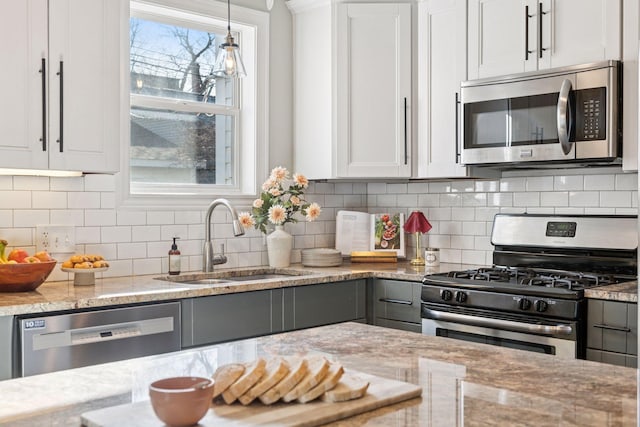 kitchen featuring backsplash, light stone counters, appliances with stainless steel finishes, and a sink