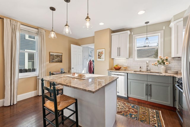 kitchen with dark wood finished floors, a center island, appliances with stainless steel finishes, and a sink