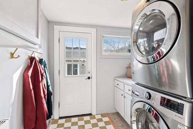 laundry room featuring cabinet space, light floors, and stacked washing maching and dryer