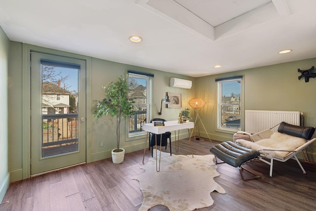 office area featuring a wall unit AC, radiator, wood finished floors, and a wealth of natural light