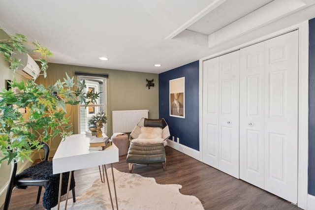 living area featuring a wall mounted air conditioner, wood finished floors, radiator heating unit, recessed lighting, and baseboards