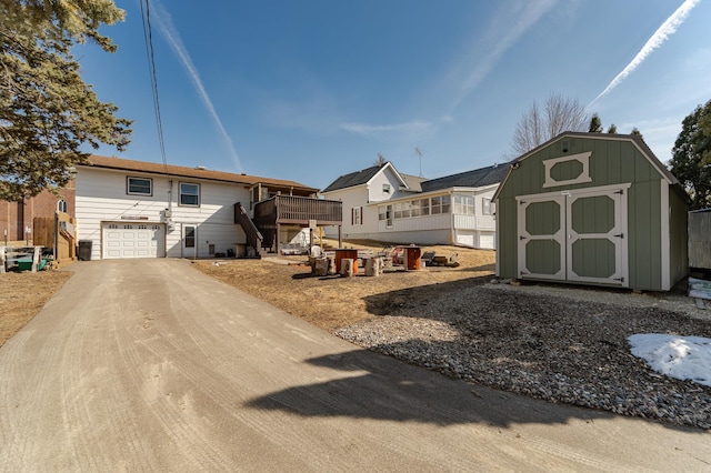 exterior space with an outbuilding, a storage unit, concrete driveway, and an attached garage