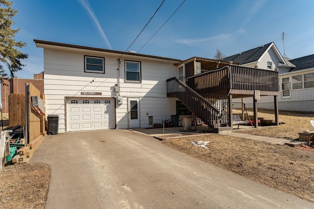 back of property with stairs, an attached garage, and driveway