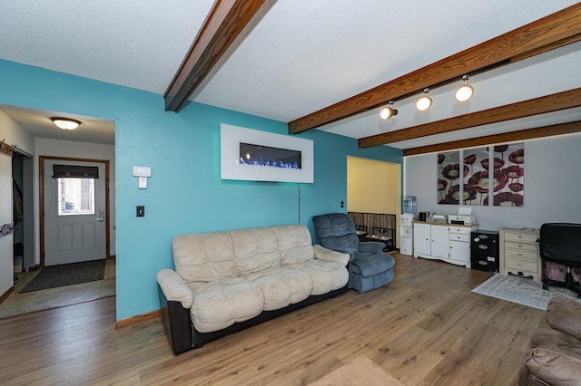 living room featuring beam ceiling, wood finished floors, baseboards, and a textured ceiling