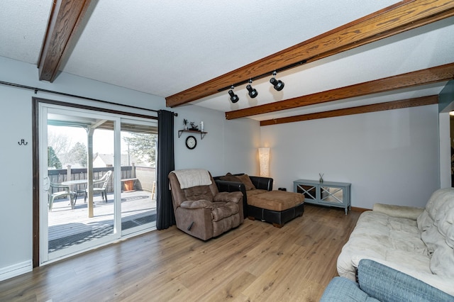 living room with beam ceiling, baseboards, light wood-type flooring, and a textured ceiling