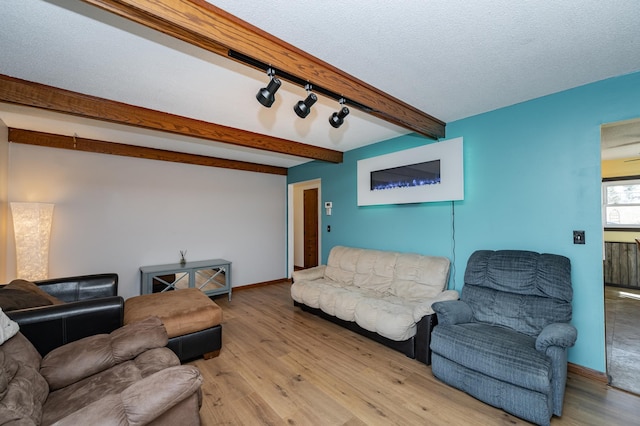 living room featuring beam ceiling, wood finished floors, baseboards, and a textured ceiling