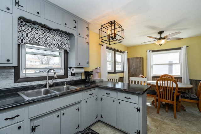 kitchen featuring a sink, dark countertops, a peninsula, and a ceiling fan