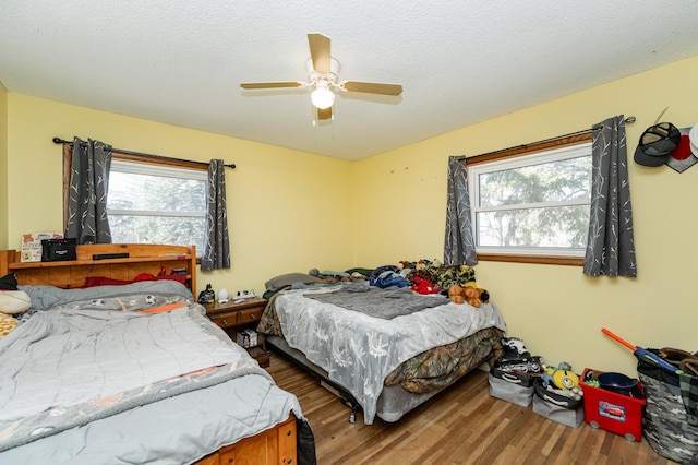 bedroom with multiple windows, wood finished floors, and a textured ceiling