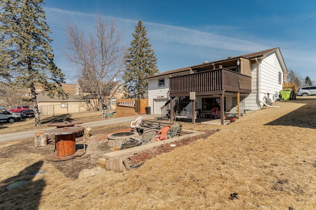 rear view of house featuring stairway, a garage, a fire pit, and a deck