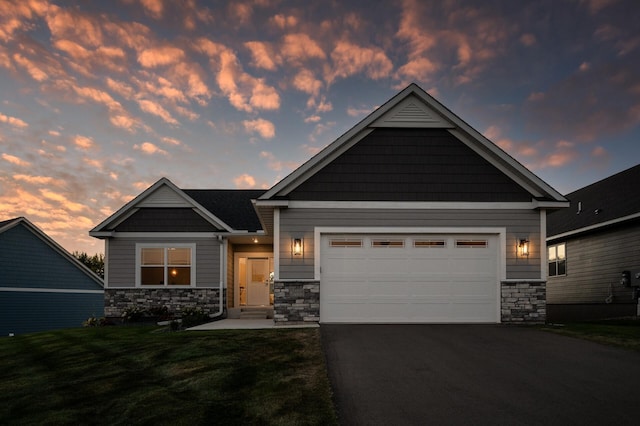 craftsman-style house with aphalt driveway, stone siding, a front yard, and an attached garage