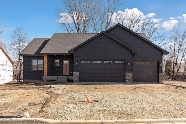 view of front of home with stone siding, an attached garage, roof with shingles, and driveway