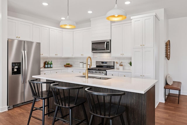 kitchen with stainless steel appliances, dark wood-type flooring, light countertops, and a sink