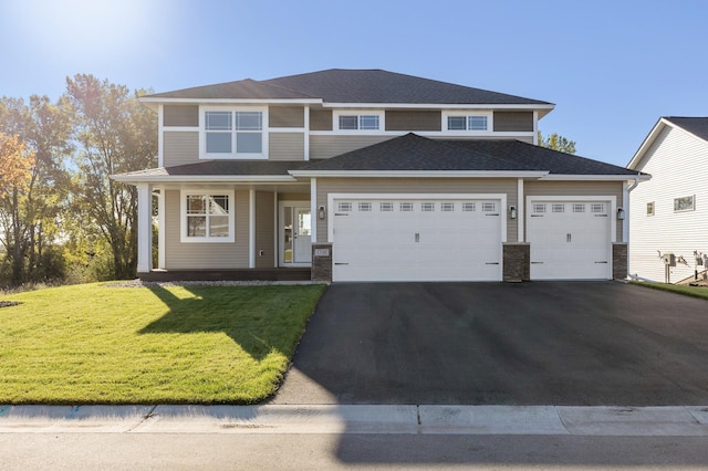 view of front of property featuring aphalt driveway, a shingled roof, covered porch, a front yard, and an attached garage