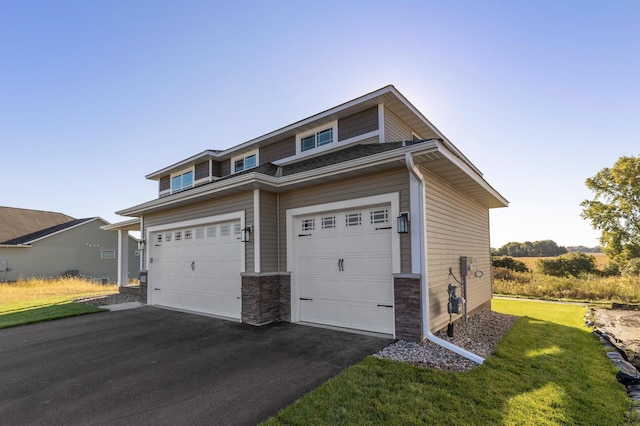 view of front of house featuring aphalt driveway, an attached garage, and a front lawn