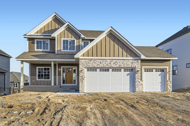 craftsman-style house featuring stone siding, roof with shingles, board and batten siding, and an attached garage