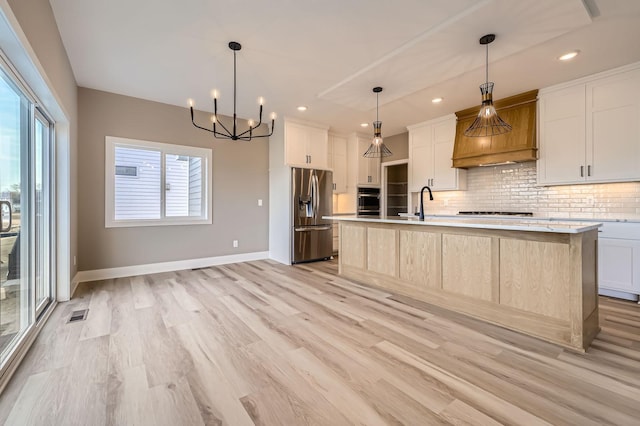 kitchen featuring tasteful backsplash, light wood finished floors, cooktop, and stainless steel refrigerator with ice dispenser