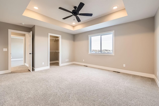 unfurnished bedroom with visible vents, baseboards, and a tray ceiling