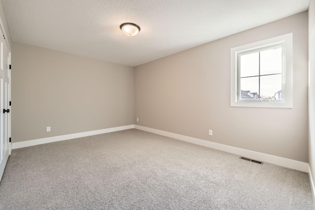 carpeted empty room with baseboards, visible vents, and a textured ceiling